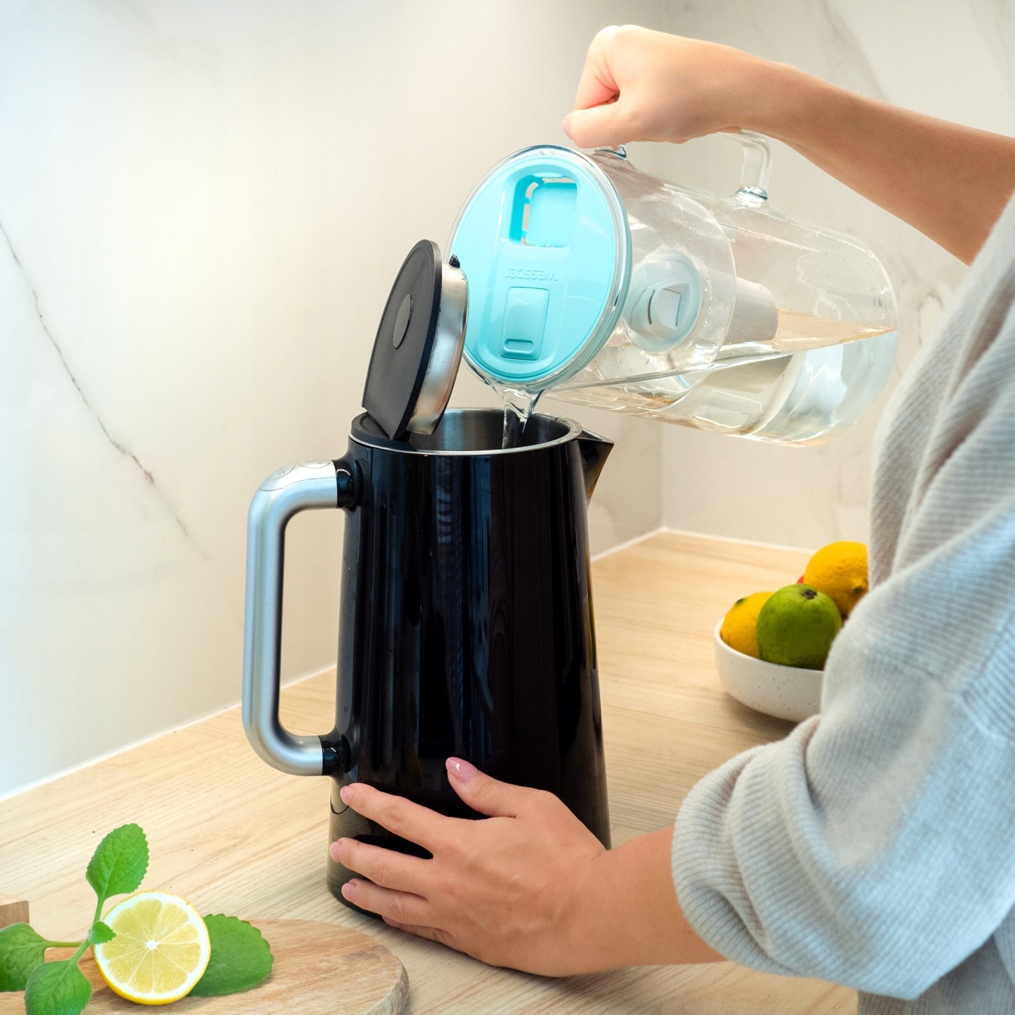 Kobiieta nalewa przefiltrowaną wodę z&nbsp;dzbanka Wessper D2 z&nbsp;licznikiem do czajnika